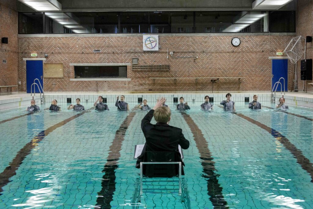 performers in the swimming pool fully clothed in line with a maestro for følsomhedsanalyser