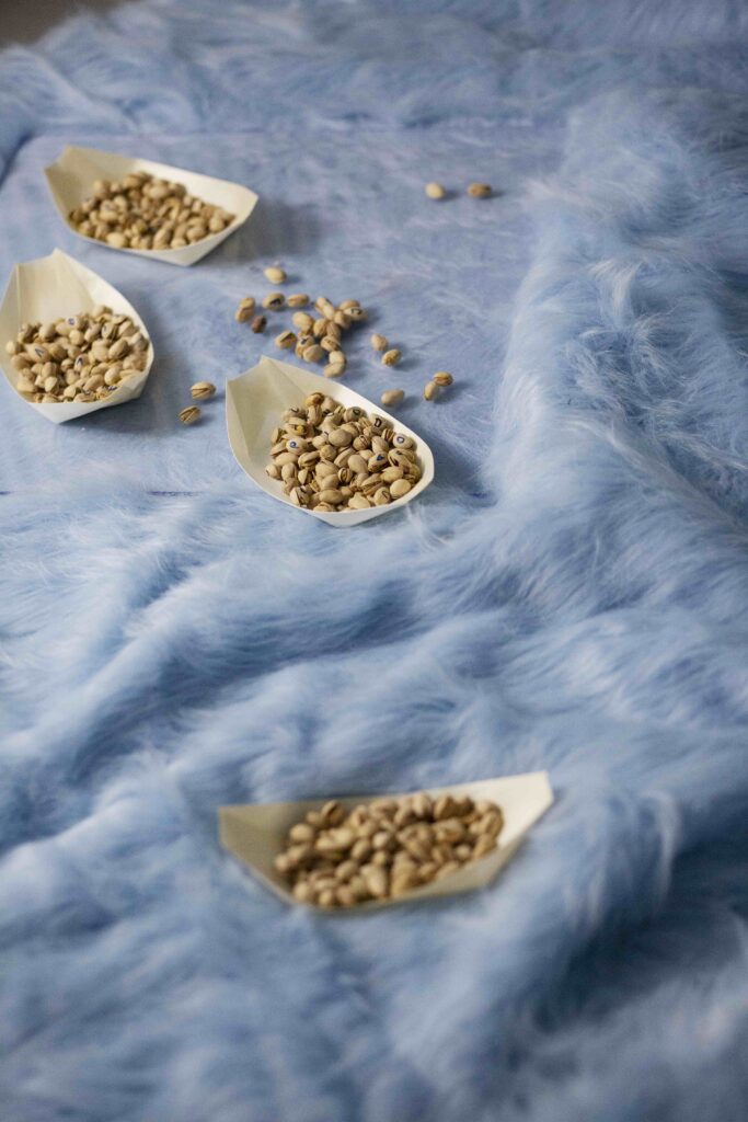 pistachios with written letters in each one in paper holder in the shape of boats in a hairy pastel blue textile